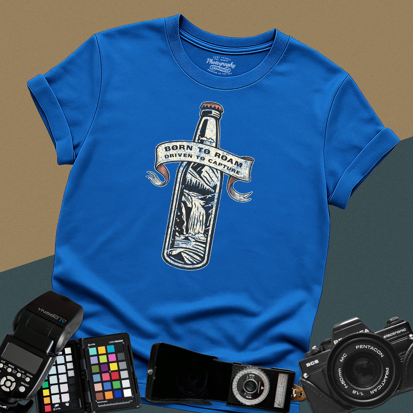 Vintage royal-blue graphic t-shirt featuring a bottle with a mountain landscape and the text "Born to Roam Driven to Capture" for travel photographers.