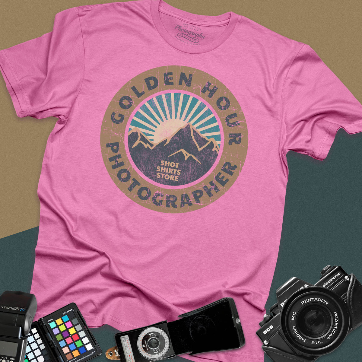 An azalea t-shirt featuring a distressed circular vintage badge design with mountain peaks and sunburst rays, surrounded by the text "Golden Hour Photographer" written along the border.
