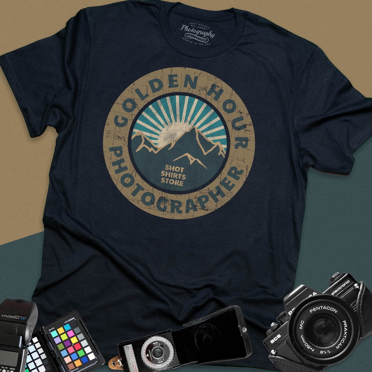 A black t-shirt featuring a distressed circular vintage badge design with mountain peaks and sunburst rays, surrounded by the text "Golden Hour Photographer" written along the border.