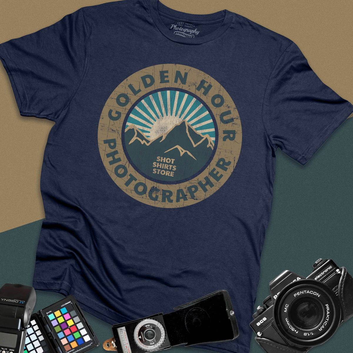 A navy blue t-shirt featuring a distressed circular vintage badge design with mountain peaks and sunburst rays, surrounded by the text "Golden Hour Photographer" written along the border.