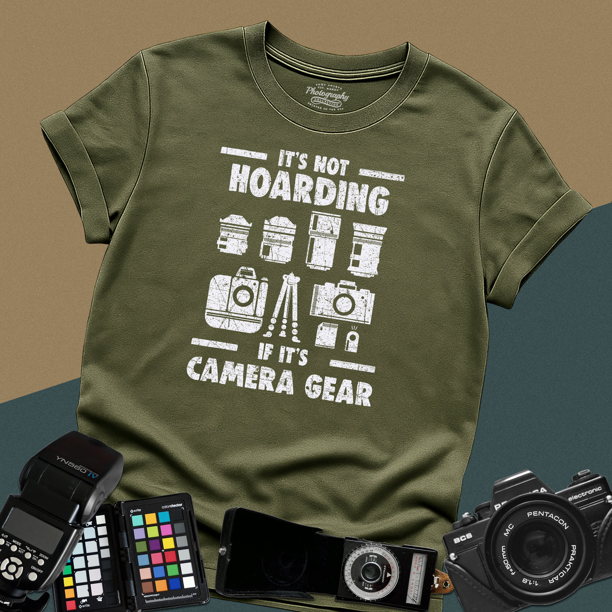 A military-green t-shirt featuring a distressed graphic with illustrations of camera bodies, lenses, and a tripod between the text "IT'S NOT HOARDING" and "IF IT'S CAMERA GEAR."