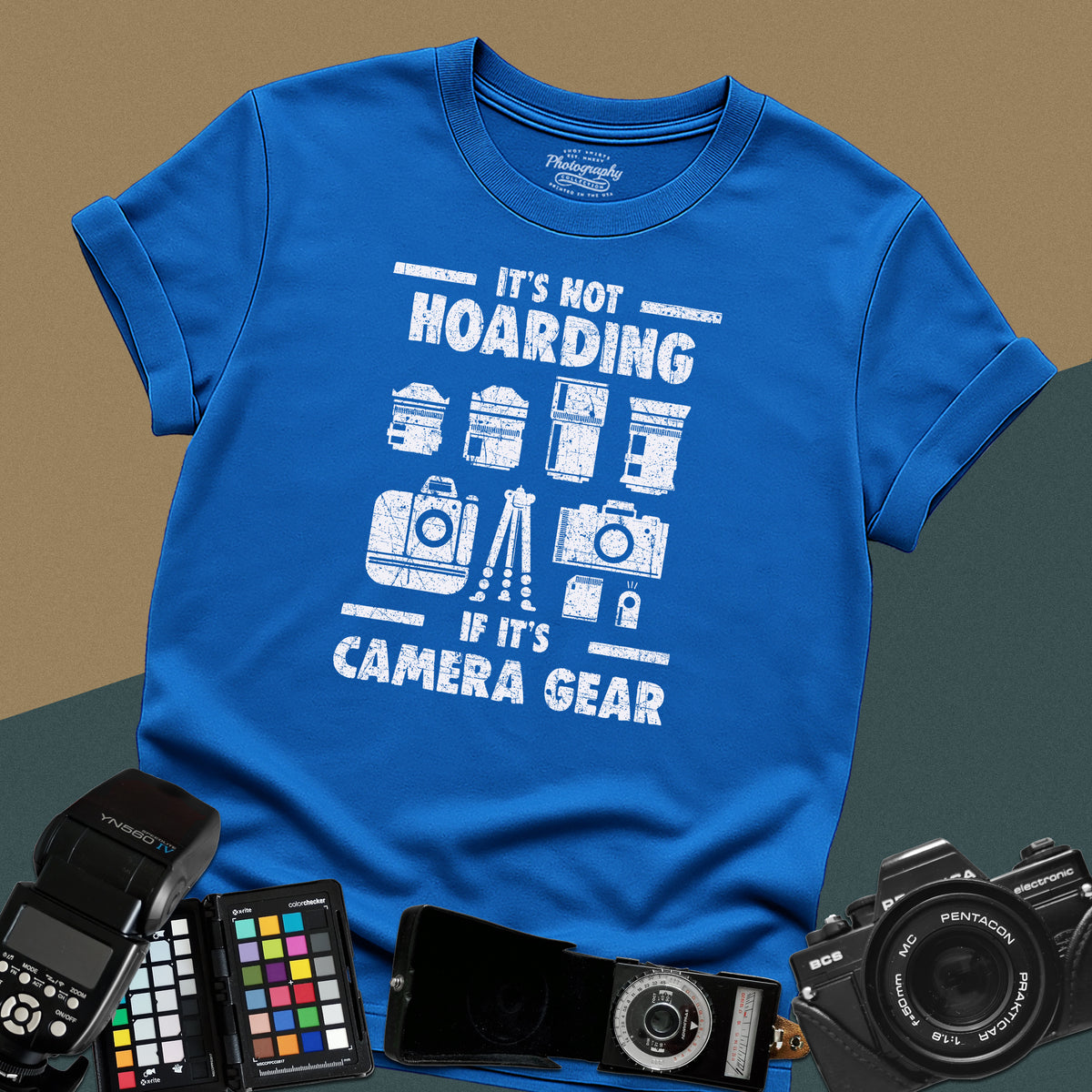 A royal-blue t-shirt featuring a distressed graphic with illustrations of camera bodies, lenses, and a tripod between the text "IT'S NOT HOARDING" and "IF IT'S CAMERA GEAR."