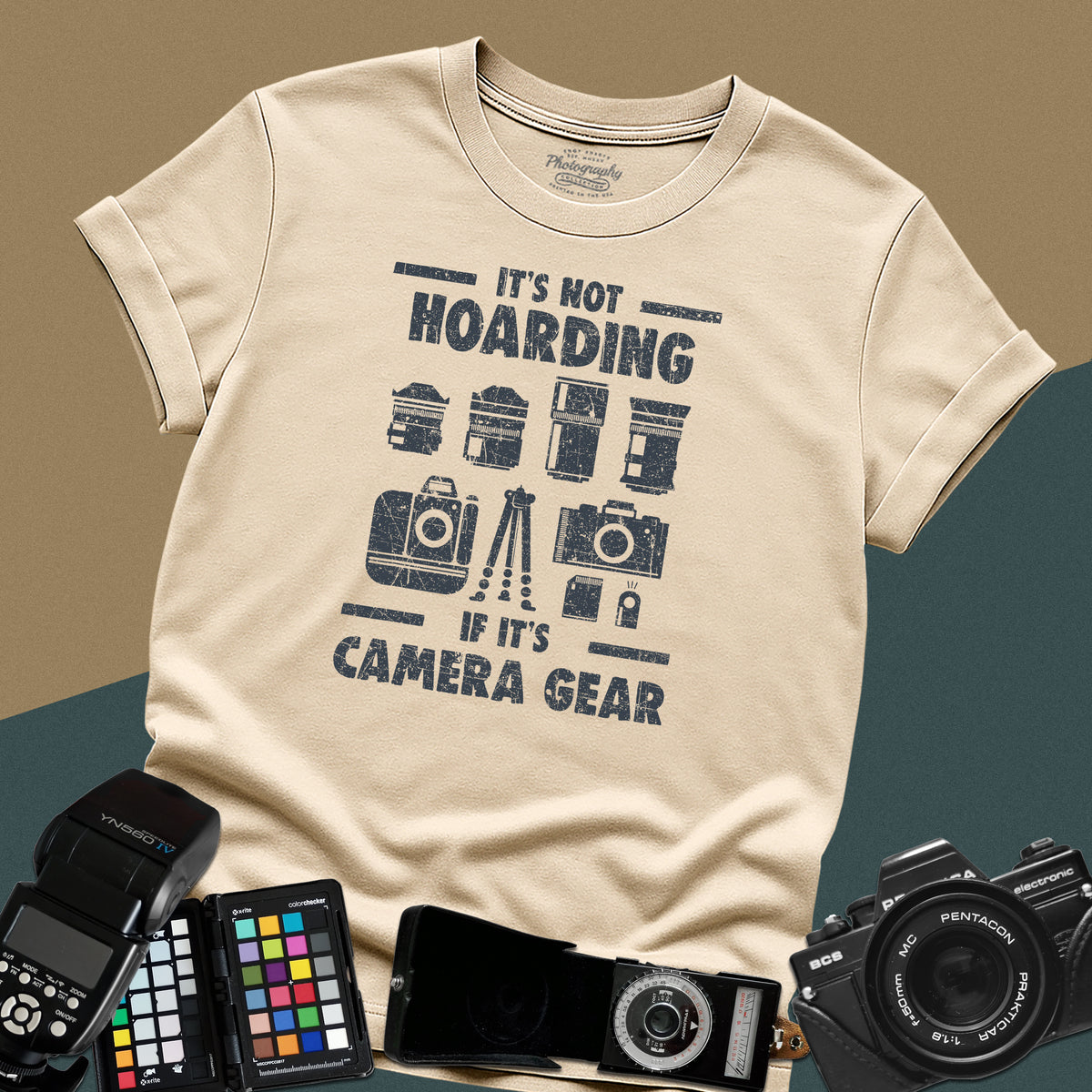 A sand t-shirt featuring a distressed graphic with illustrations of camera bodies, lenses, and a tripod between the text "IT'S NOT HOARDING" and "IF IT'S CAMERA GEAR."