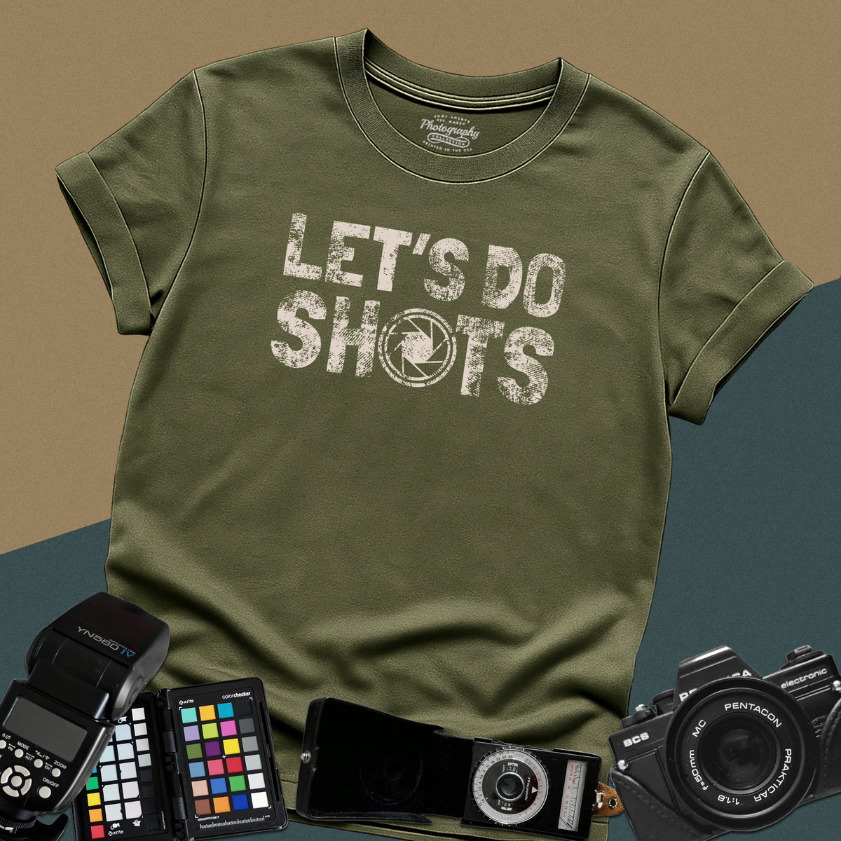 Heavy distressed military-green t-shirt featuring bold retro typography text "Let's Do Shots" with a camera aperture lens icon inside the letter O.