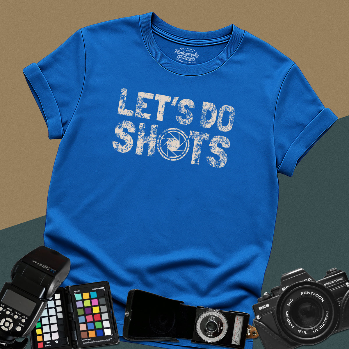 Heavy distressed royal-blue t-shirt featuring bold retro typography text "Let's Do Shots" with a camera aperture lens icon inside the letter O.