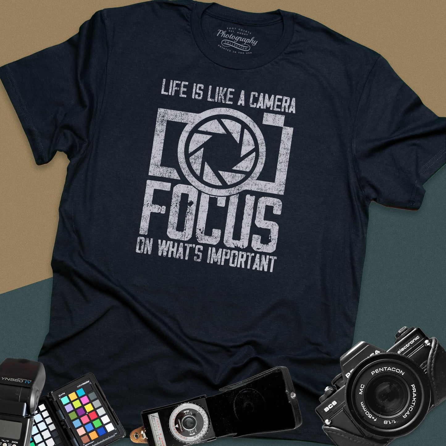 Distressed black t-shirt featuring a large retro camera silhouette with an aperture shutter lens graphic and inspirational photography quote typography.