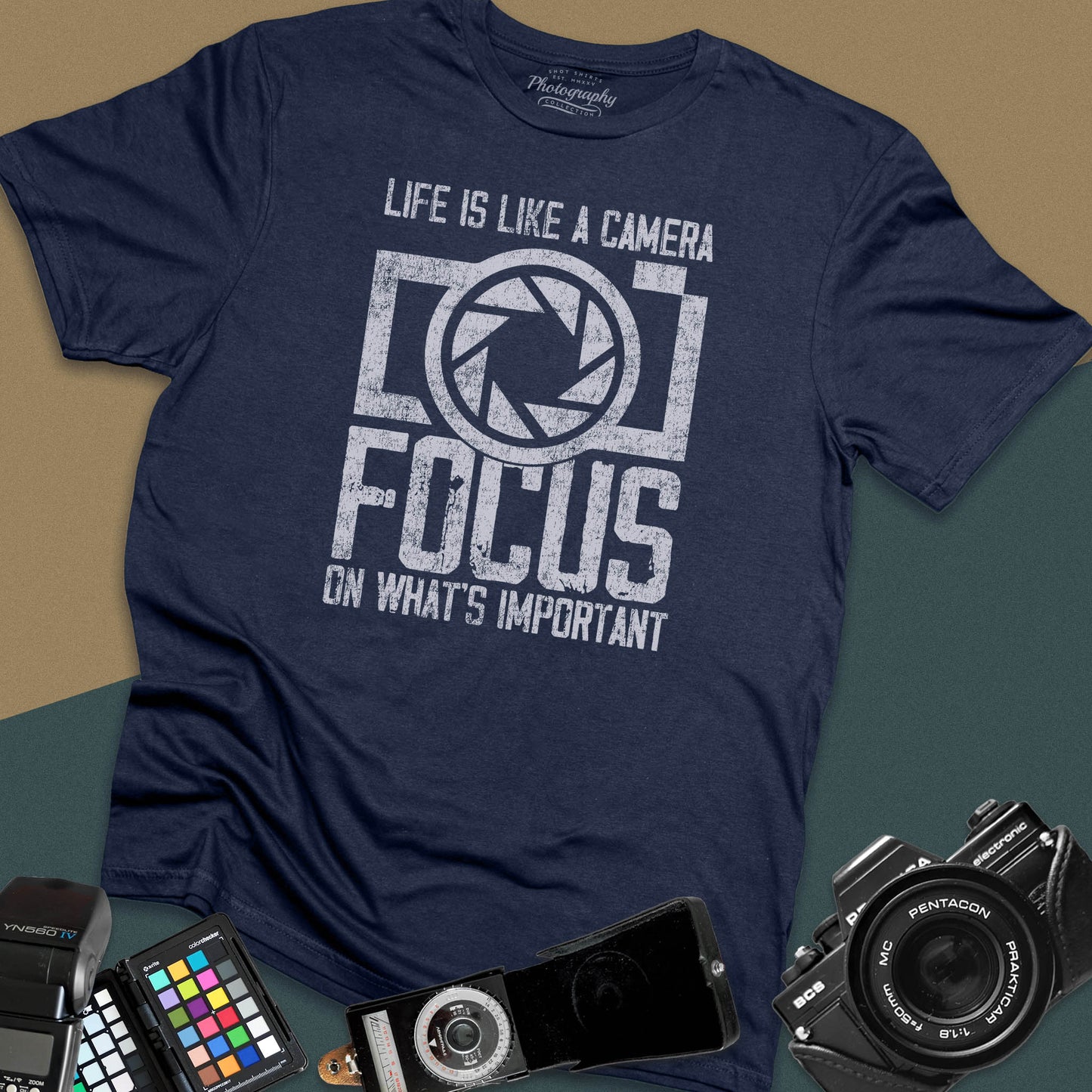 Distressed navy-blue t-shirt featuring a large retro camera silhouette with an aperture shutter lens graphic and inspirational photography quote typography.