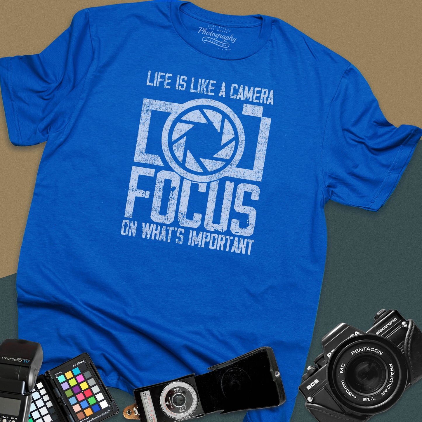 Distressed royal-blue t-shirt featuring a large retro camera silhouette with an aperture shutter lens graphic and inspirational photography quote typography.