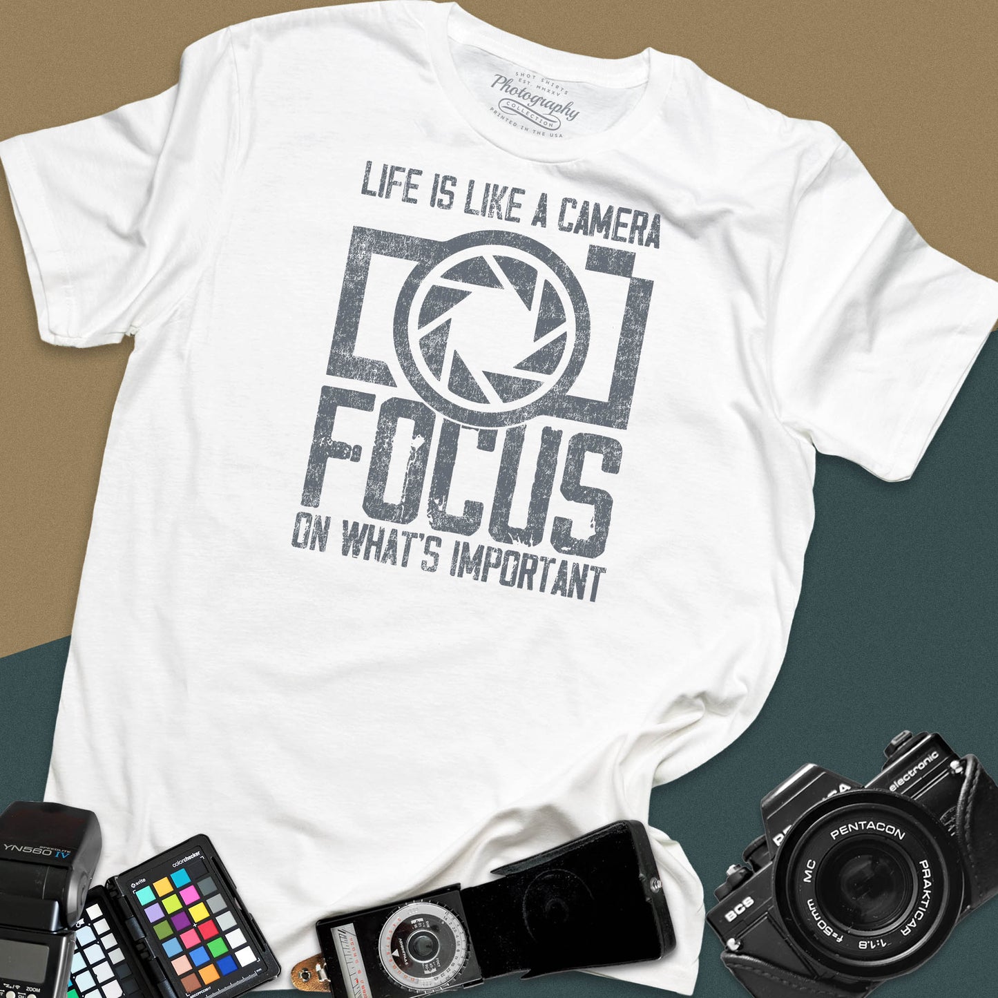 Distressed white t-shirt featuring a large retro camera silhouette with an aperture shutter lens graphic and inspirational photography quote typography.