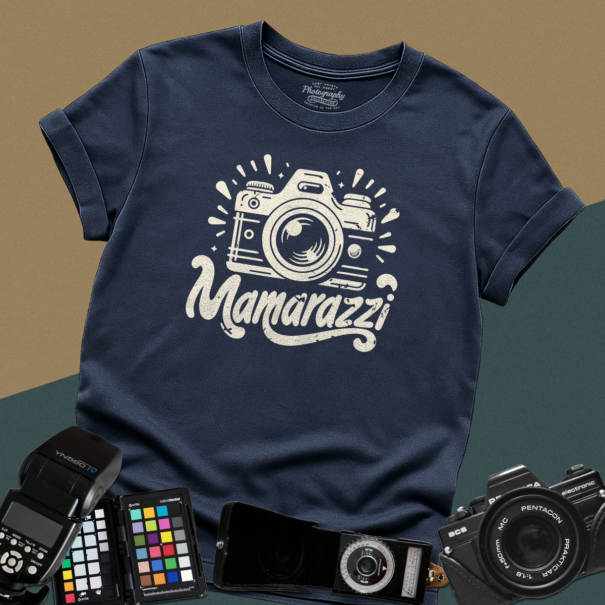 A navy-blue t-shirt featuring a distressed vintage camera graphic with sparkles and the stylized text "Mamarazzi" written in a retro script font across the chest.