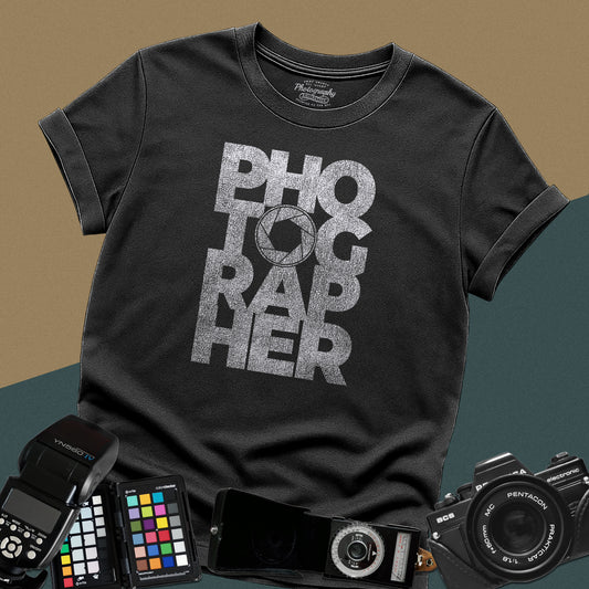 Clean black t-shirt featuring a geometric bold block typography design spelling photographer with a camera aperture lens icon inside the letter O.