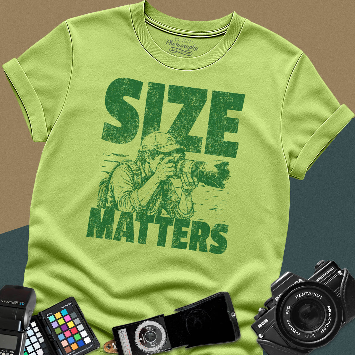 A kiwi green t-shirt featuring a distressed graphic of a photographer looking through a camera with a huge telephoto lens between the text "SIZE" and "MATTERS" in bold letters.
