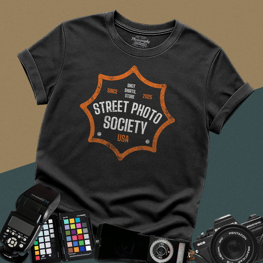 Distressed black t-shirt featuring a retro shield badge emblem with Street Photo Society USA typography for urban documentary photographers.