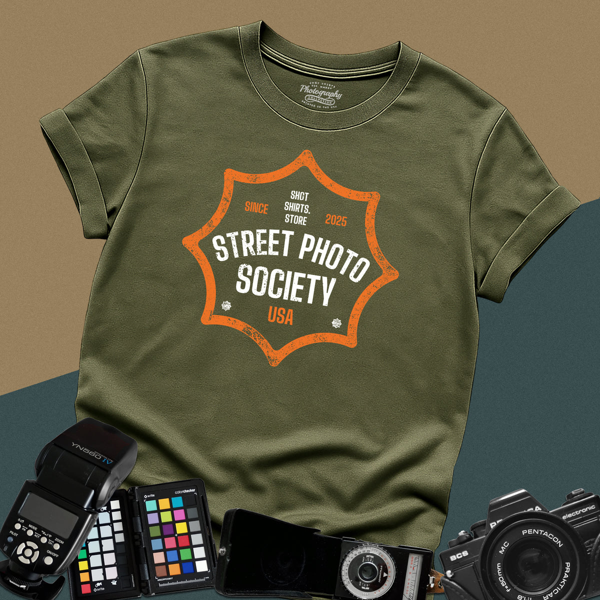 Distressed military-green t-shirt featuring a retro shield badge emblem with Street Photo Society USA typography for urban documentary photographers.